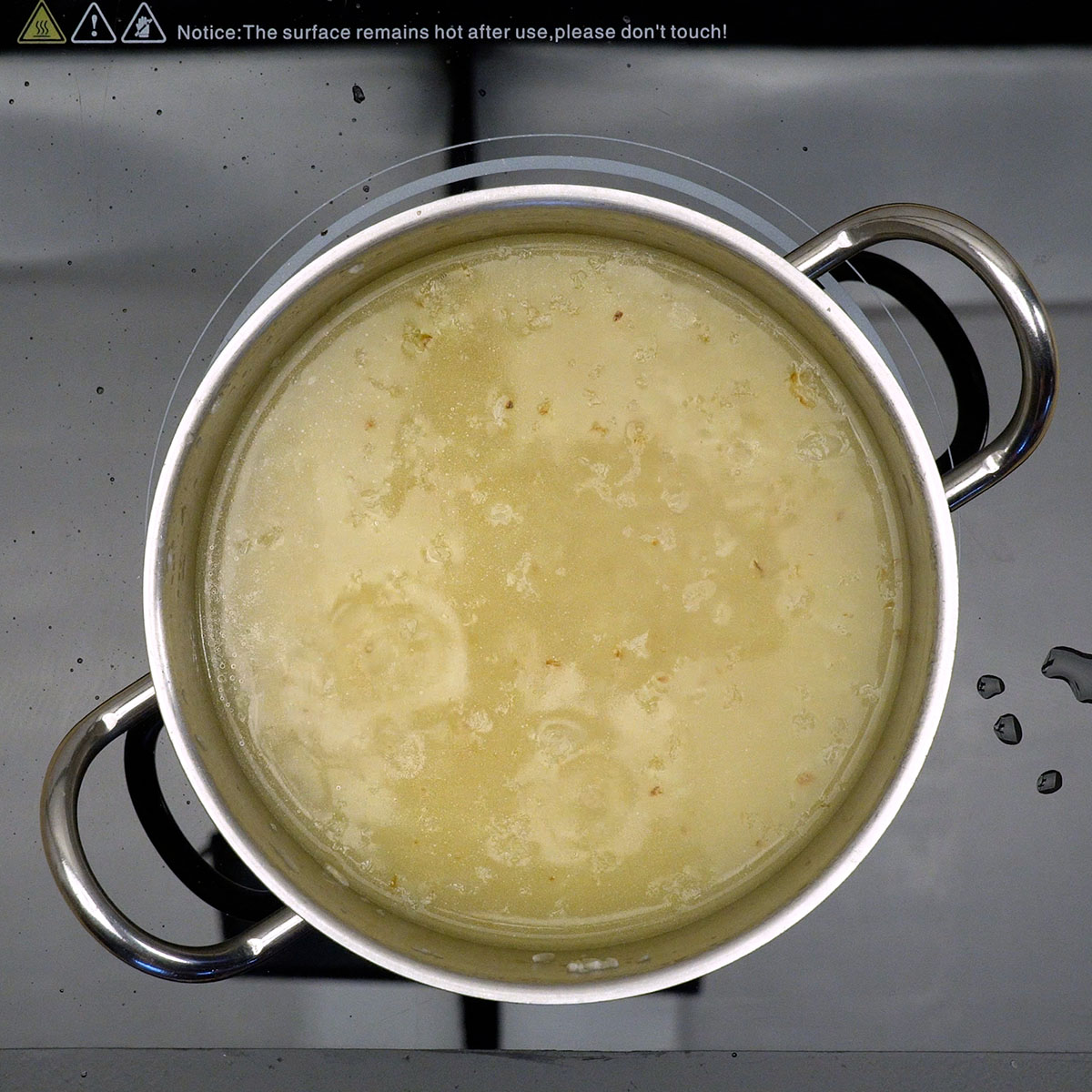 Arroz cozinhando na panela com água quente até amolecer uniformemente.