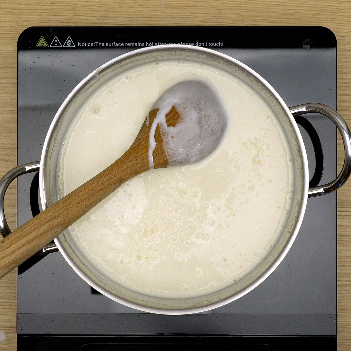 Creme sendo engrossado com farinha e creme de leite, mexendo constantemente.