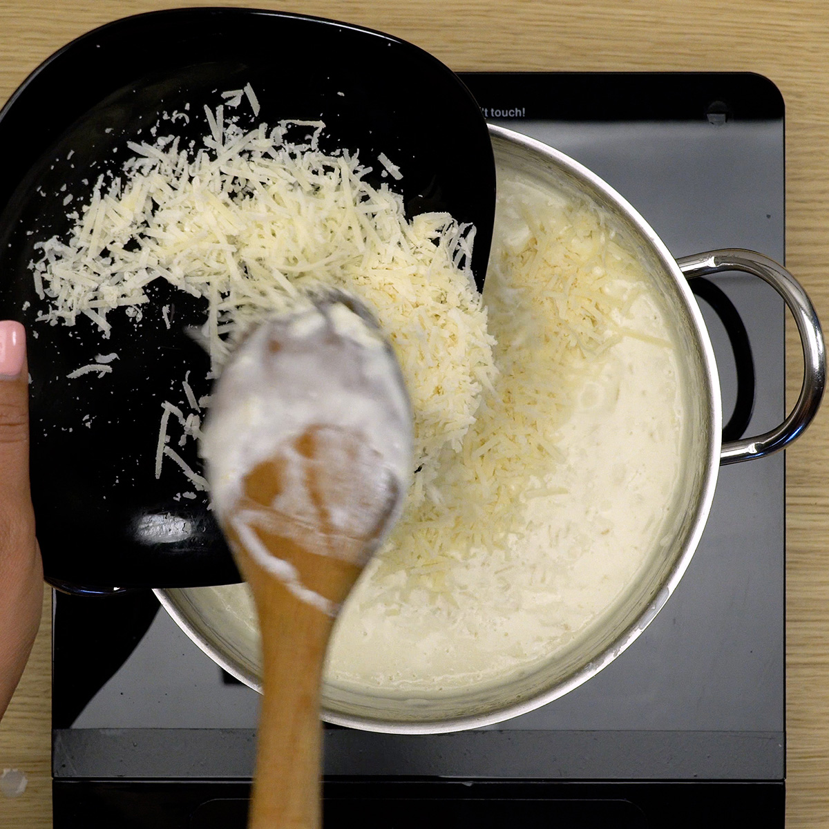 Arroz sendo misturado ao creme e finalizado com queijo parmesão ralado.