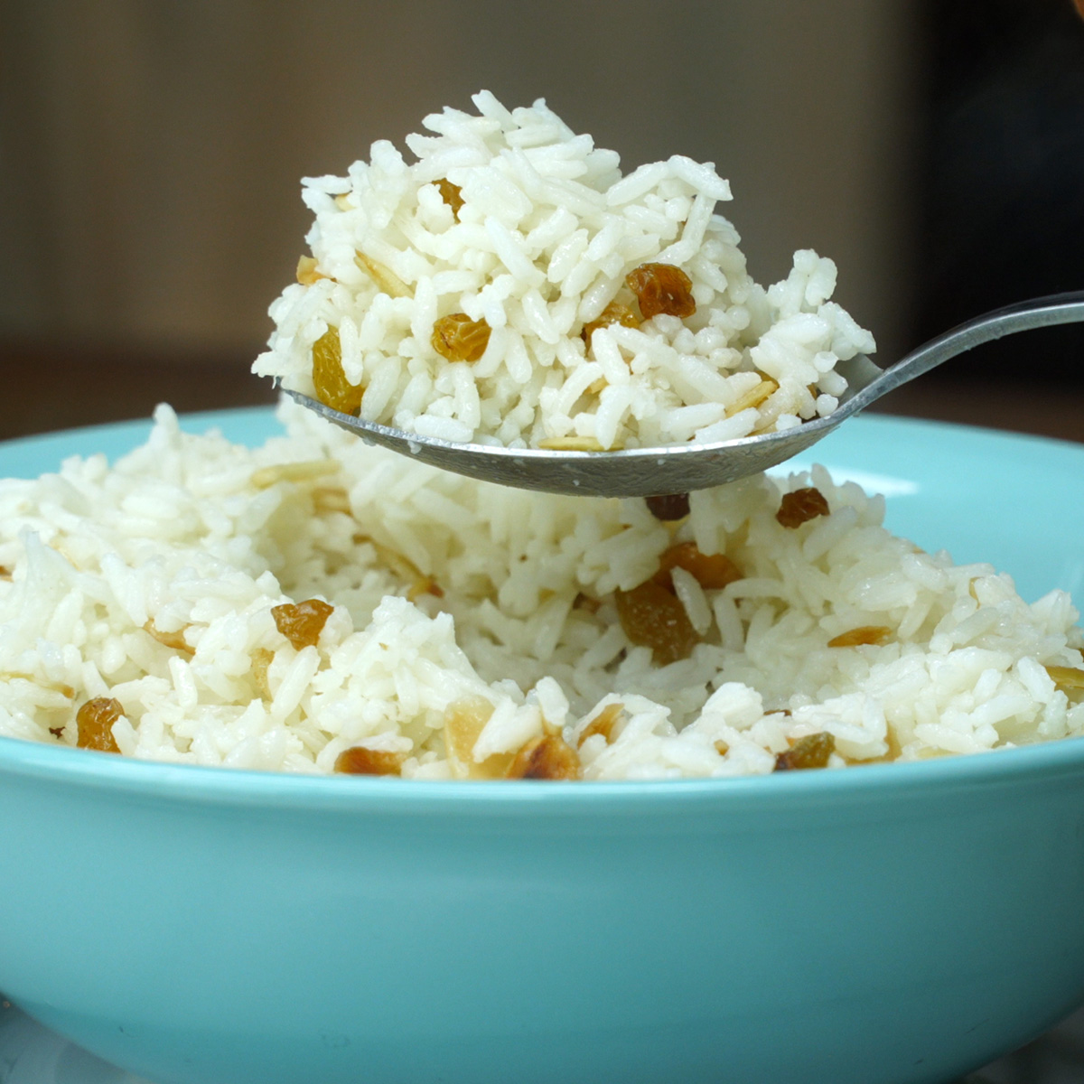 Arroz com sultanas e amêndoas sendo servido.