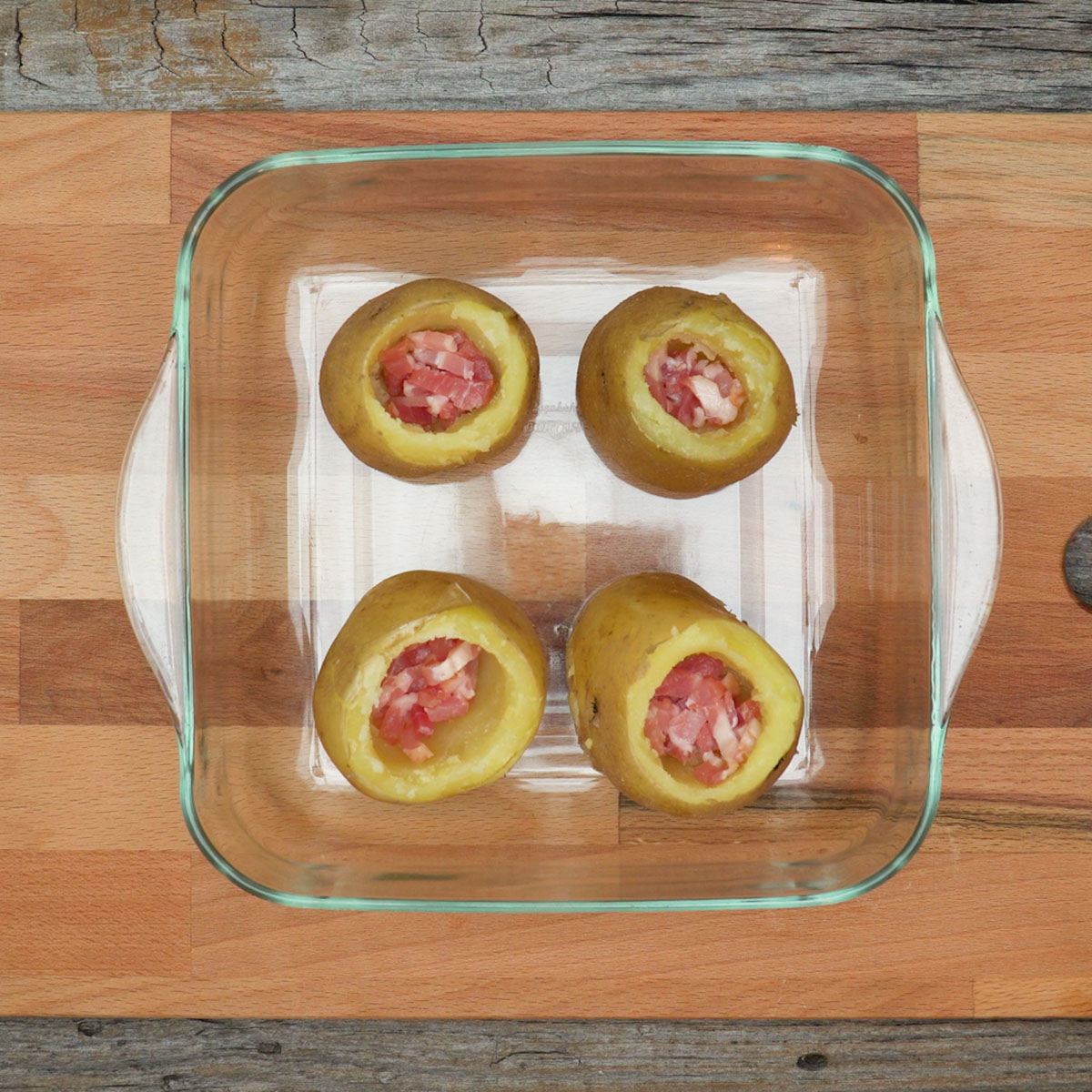 Batatas sendo recheadas com bacon e queijo para ir ao forno.