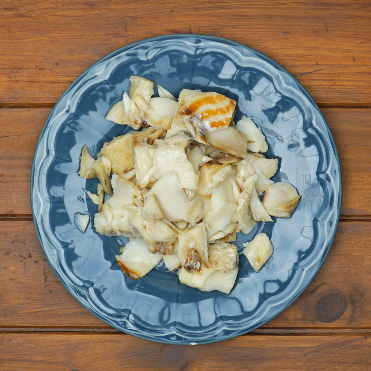 Bacalhau sendo desfiado em lascas após o cozimento.