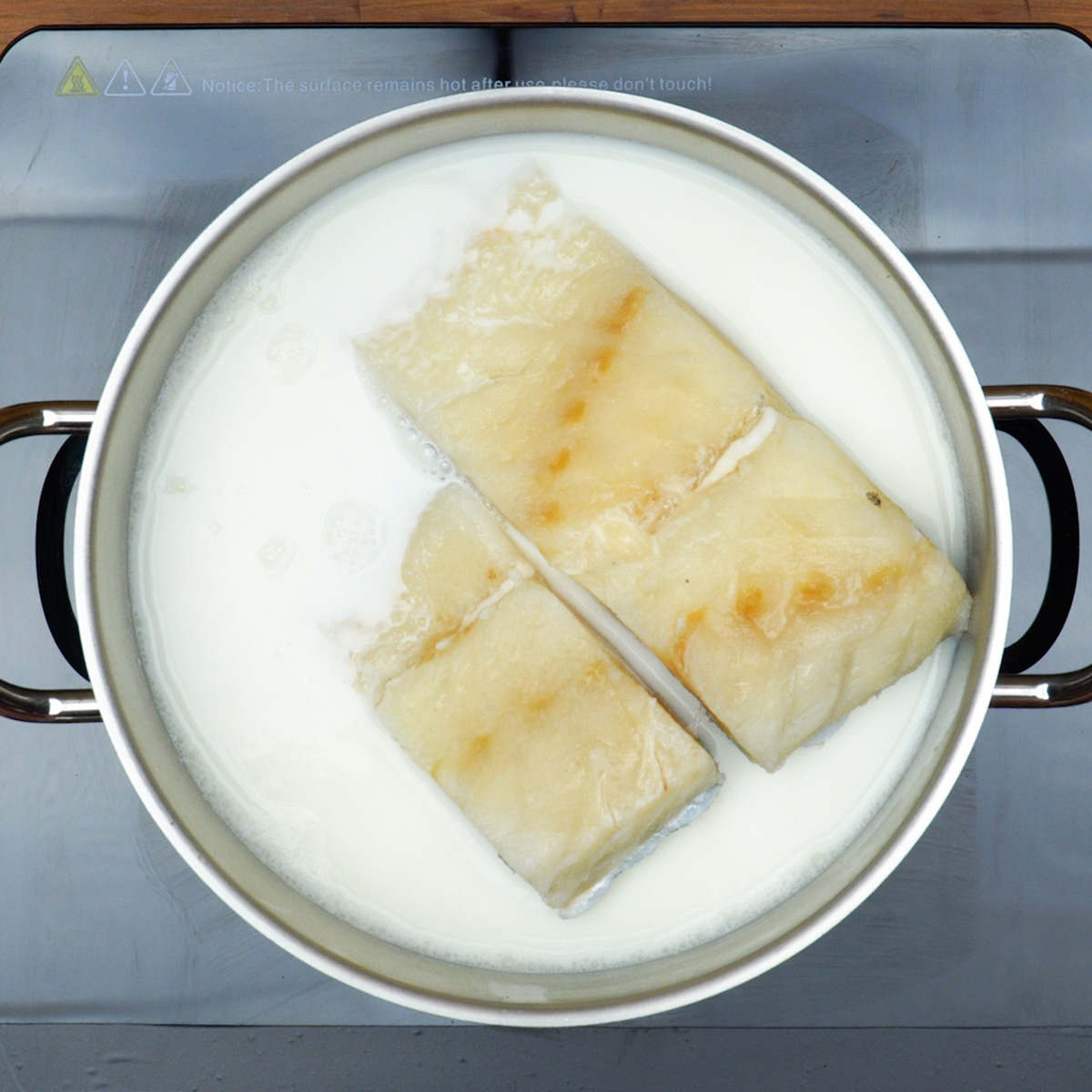 Postas de bacalhau cozinhando no leite.