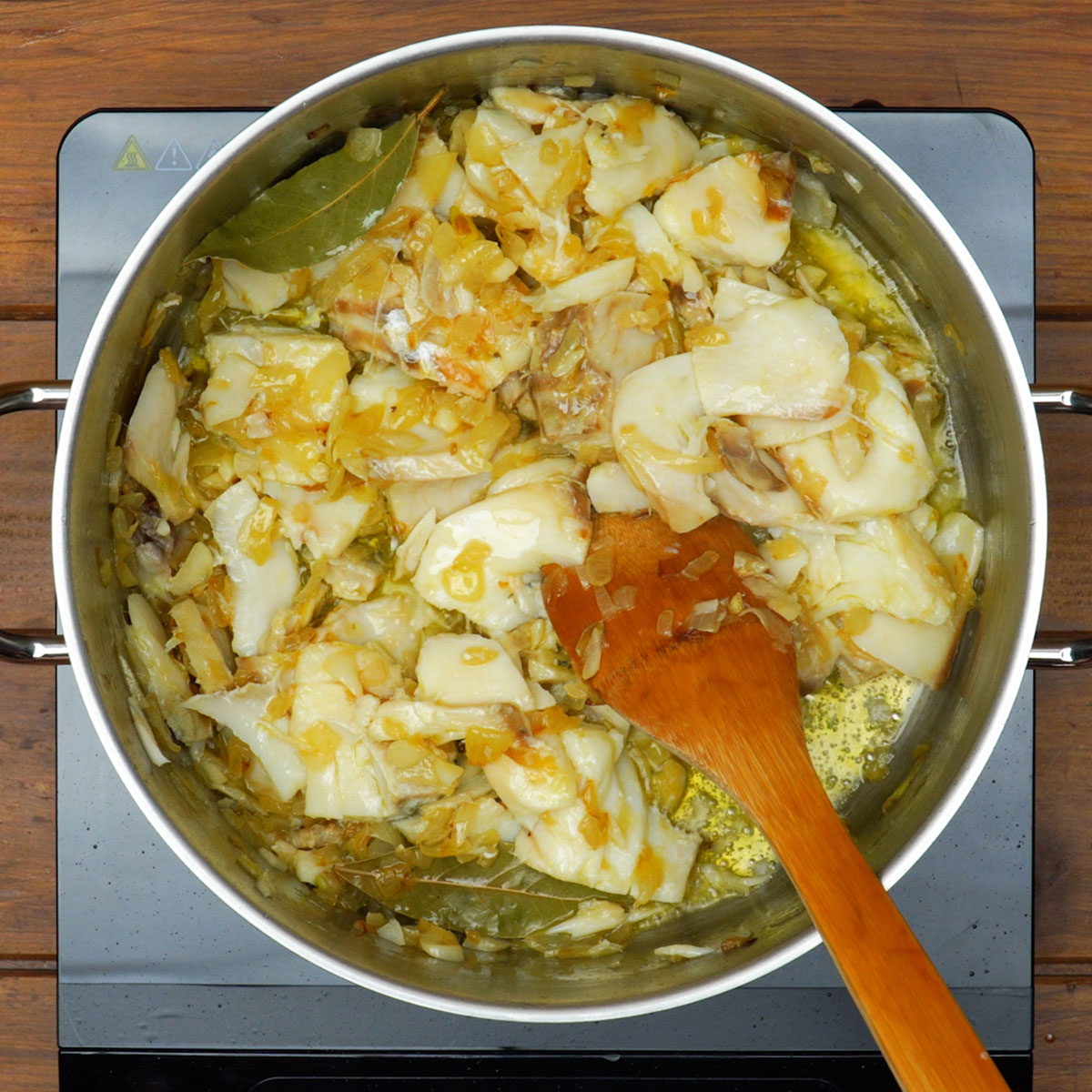 Bacalhau sendo refogado com cebola e alho.