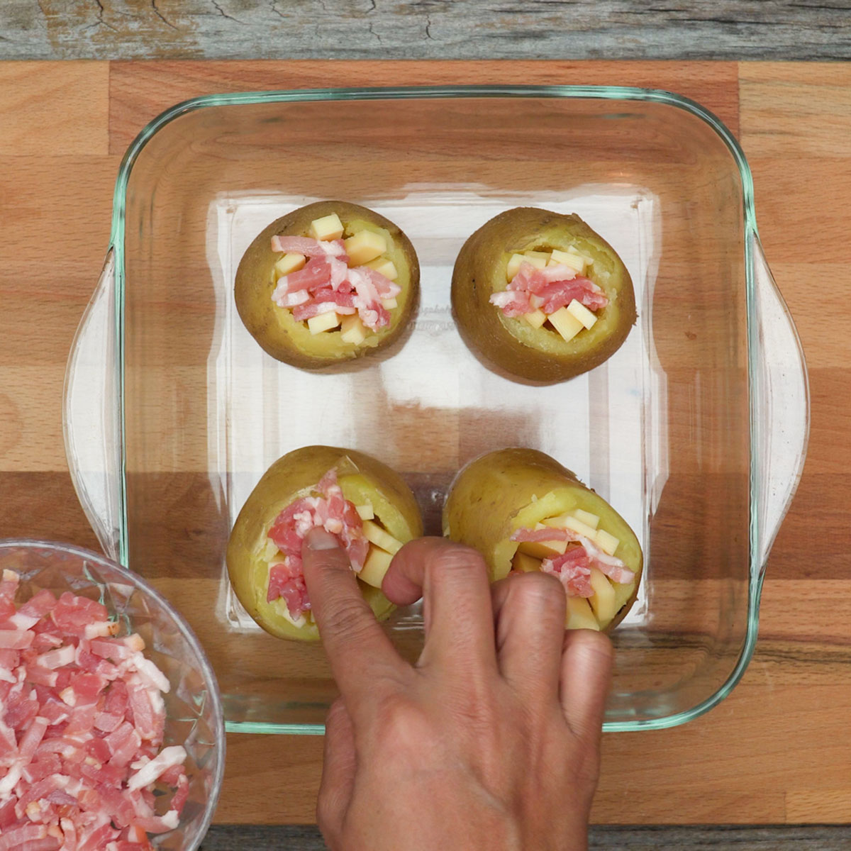 Batatas recheadas com camadas de bacon e queijo antes de assar.