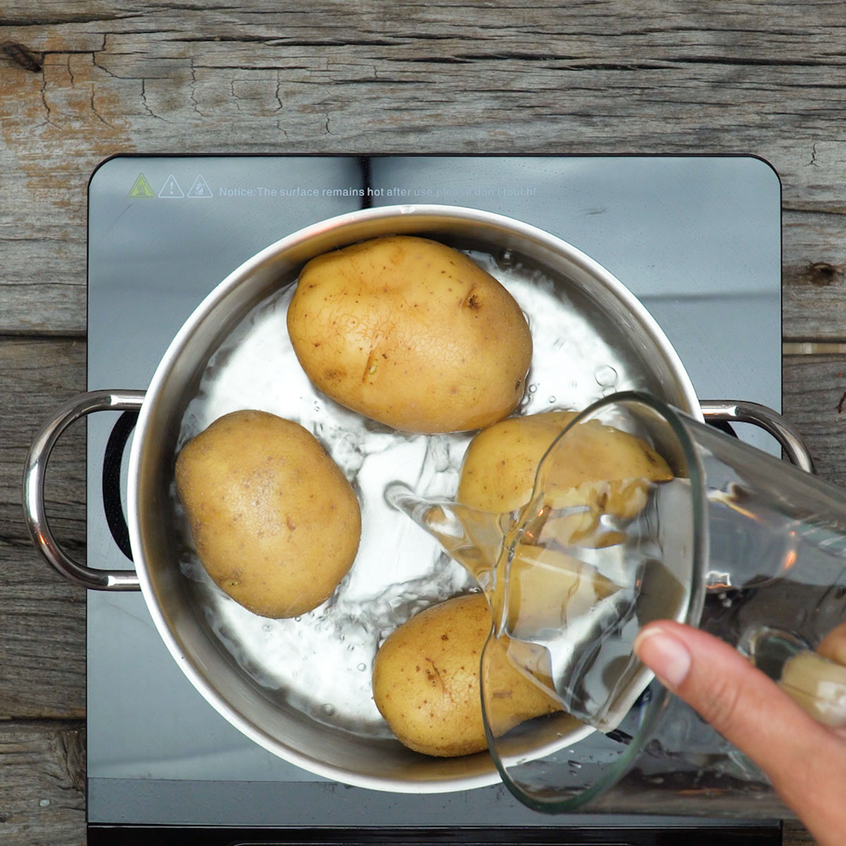 Batatas grandes cozinhando para preparar batata recheada com bacon e queijo.