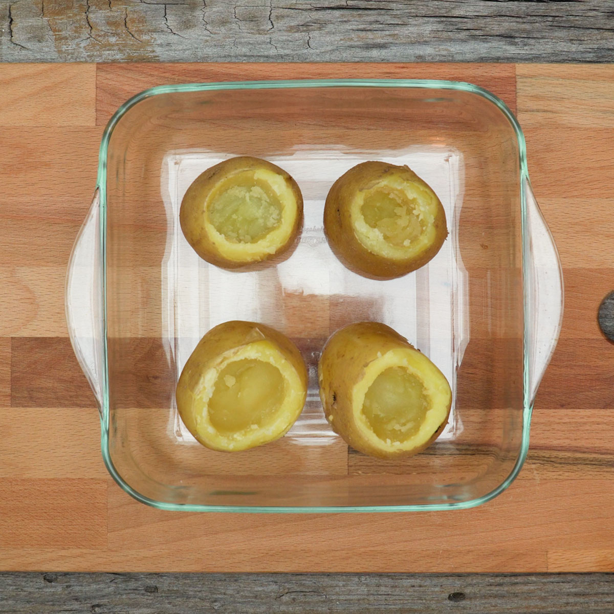 Batatas escavadas com colher para preparar batata recheada com bacon e queijo.