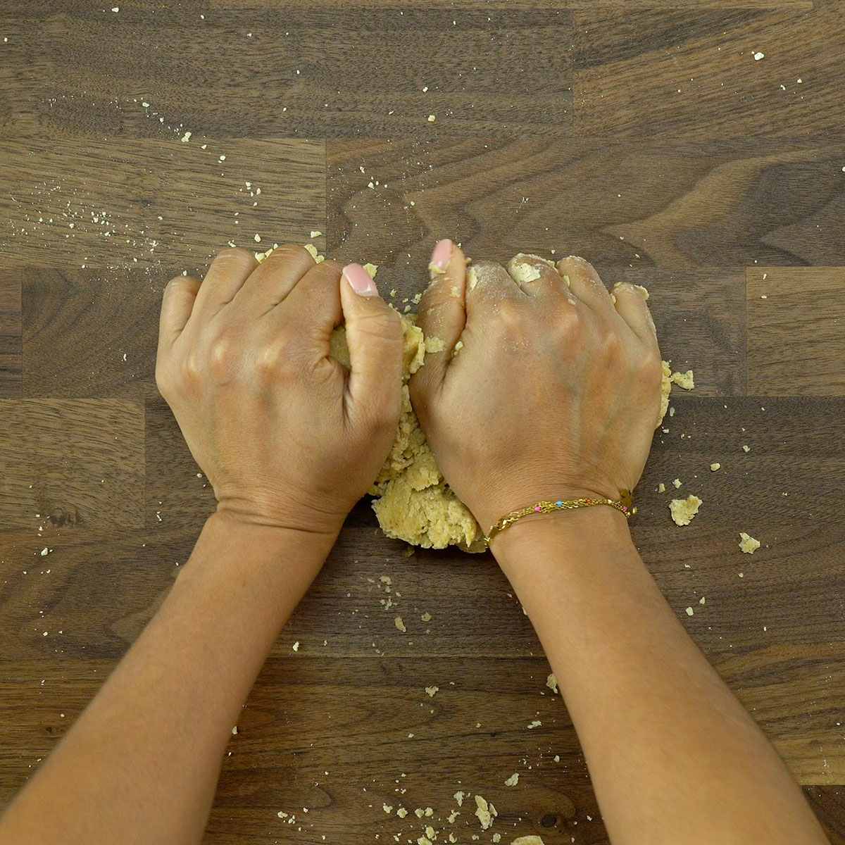 Massa de biscoito salgado sendo trabalhada sobre bancada enfarinhada.