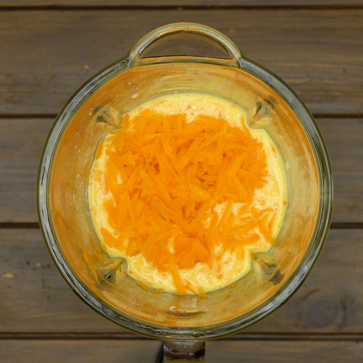 Cenoura ralada sendo incorporada à mistura no liquidificador.