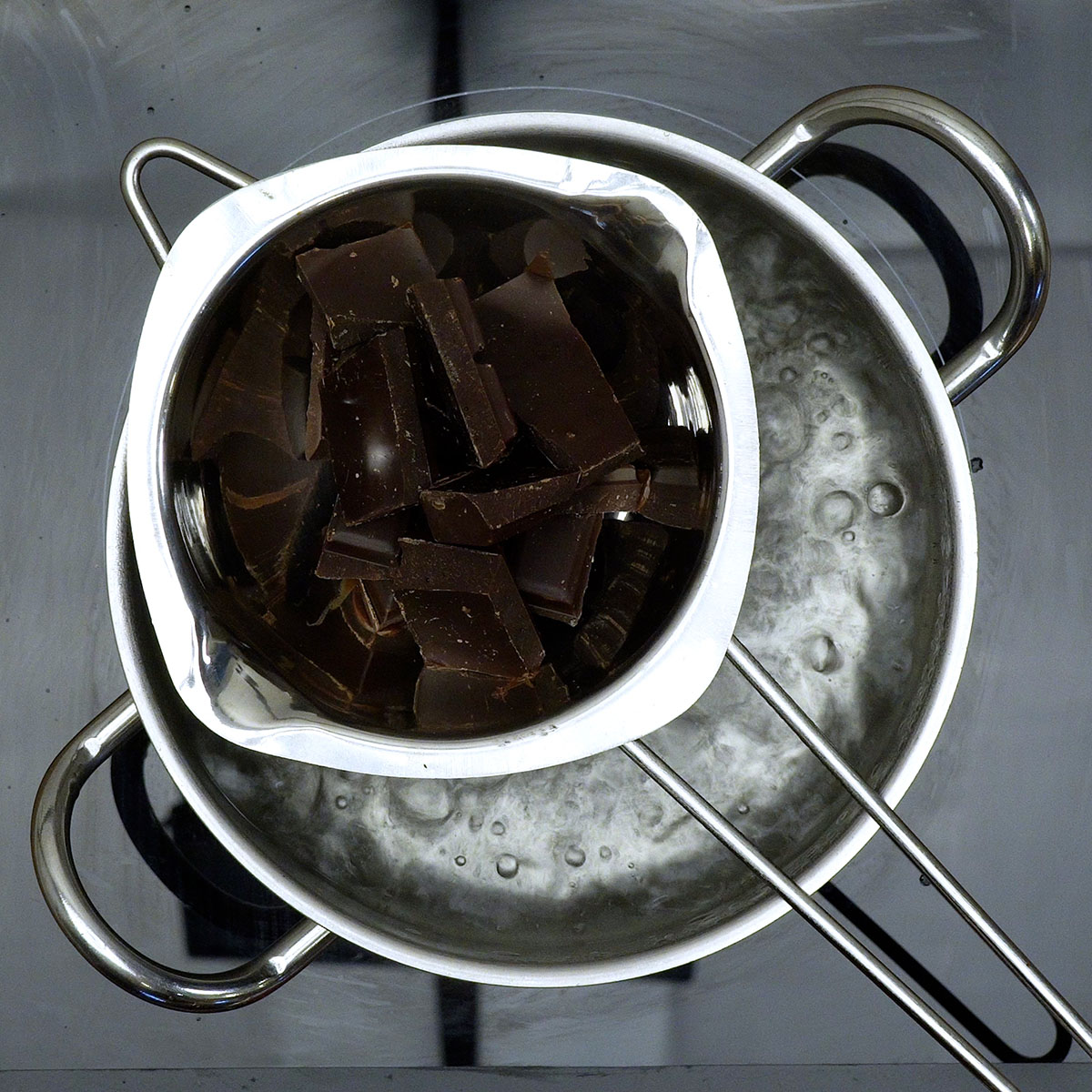 Chocolate sendo derretido em banho-maria até ficar liso e brilhante.