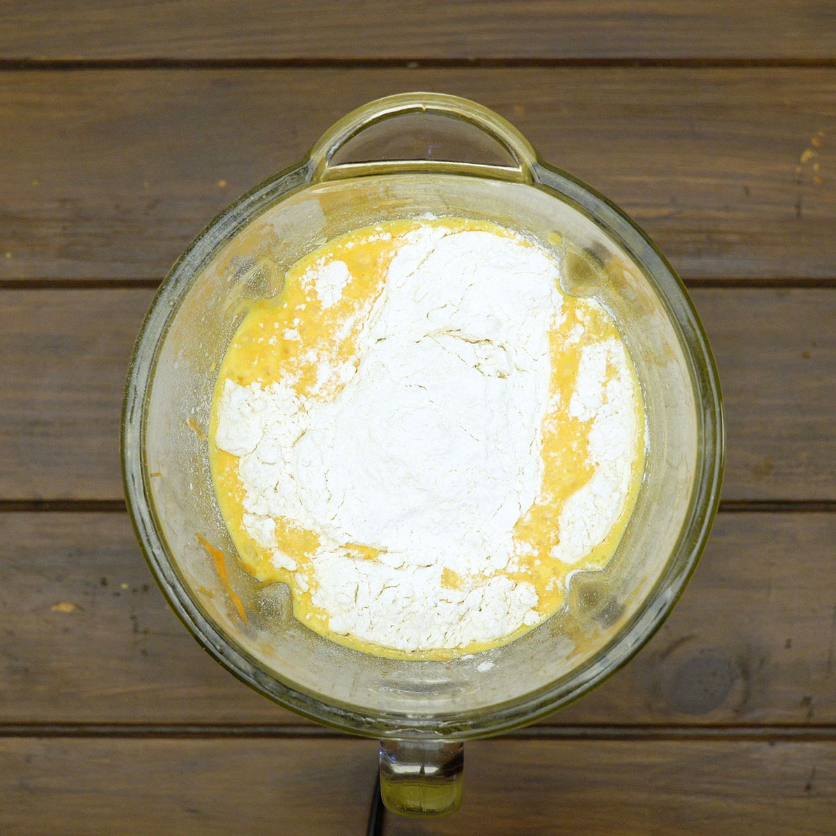 Massa de bolo de cenoura sendo misturada com farinha usando uma espátula.