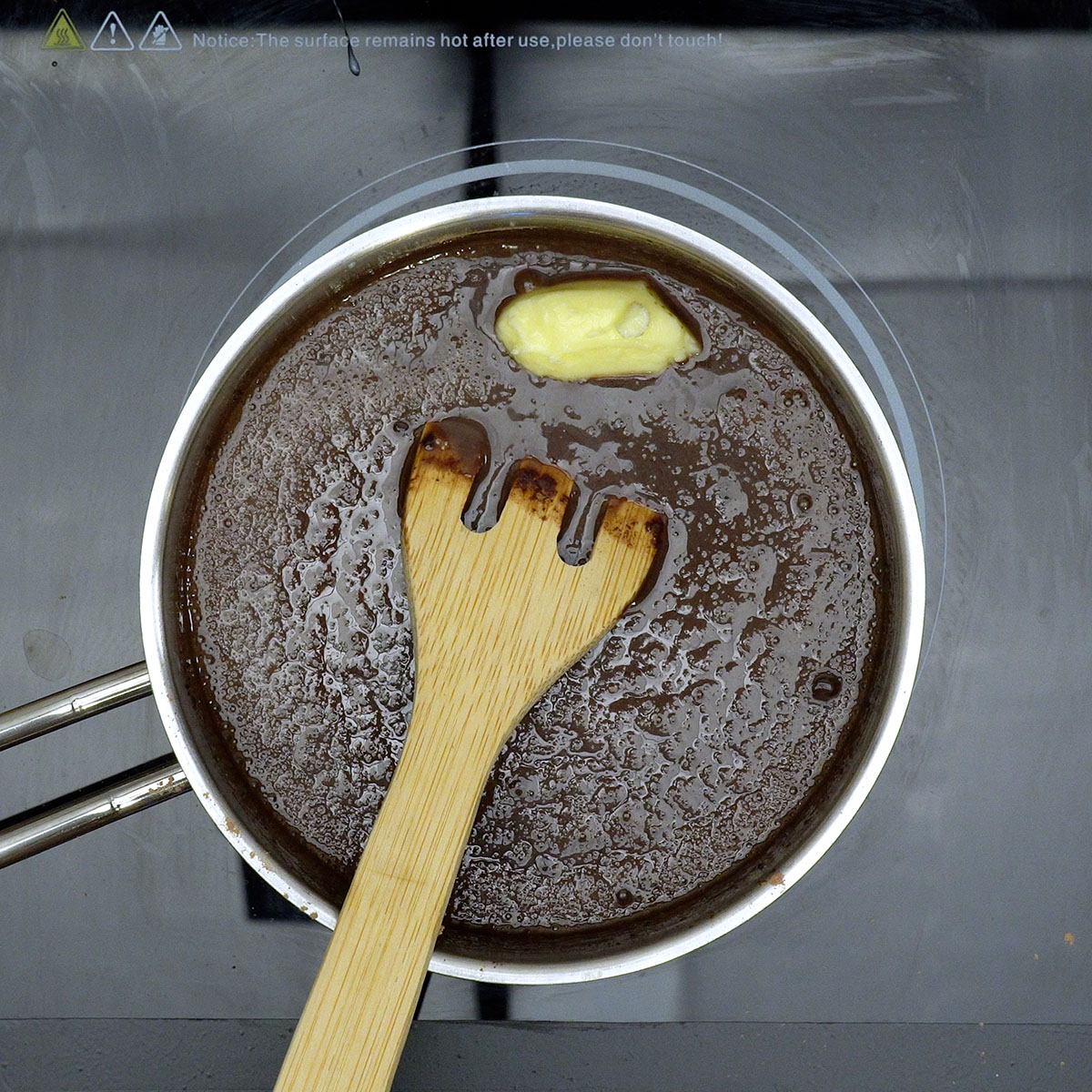 Mistura de leite condensado, creme de leite, manteiga e chocolate formando uma cobertura cremosa.