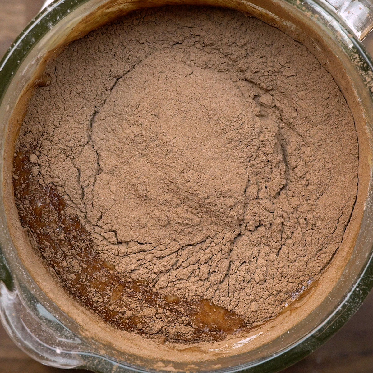 Chocolate em pó sendo misturado à massa de bolo de chocolate com uma colher.
