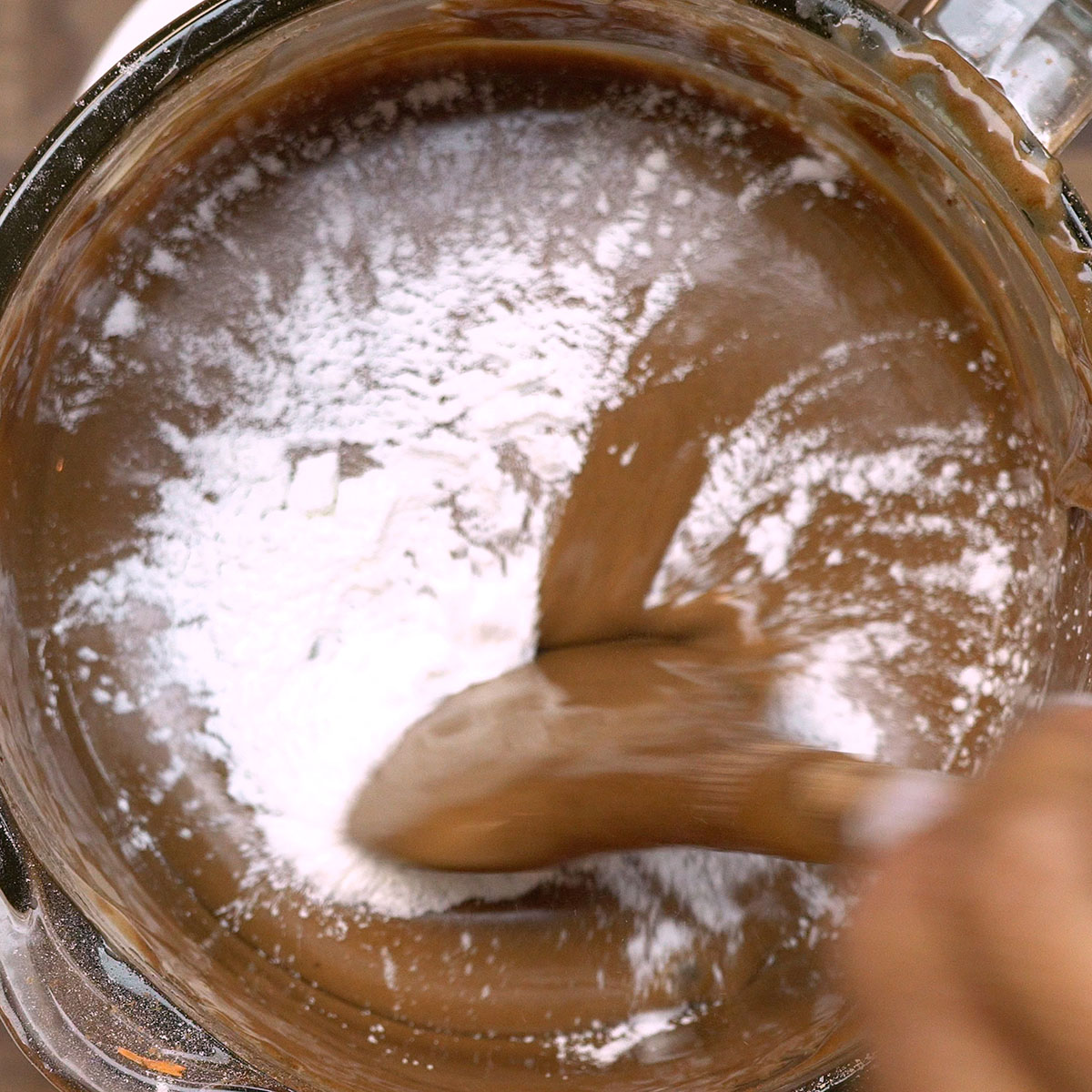 Fermento sendo misturado suavemente à massa de bolo de chocolate.