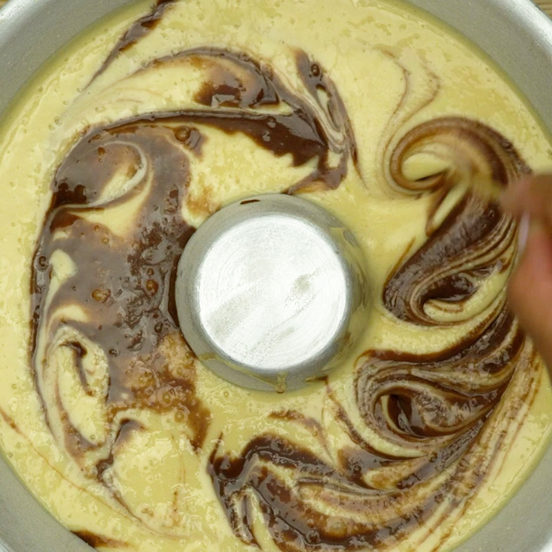 Efeito mesclado do bolo mármore sendo criado com um palito.