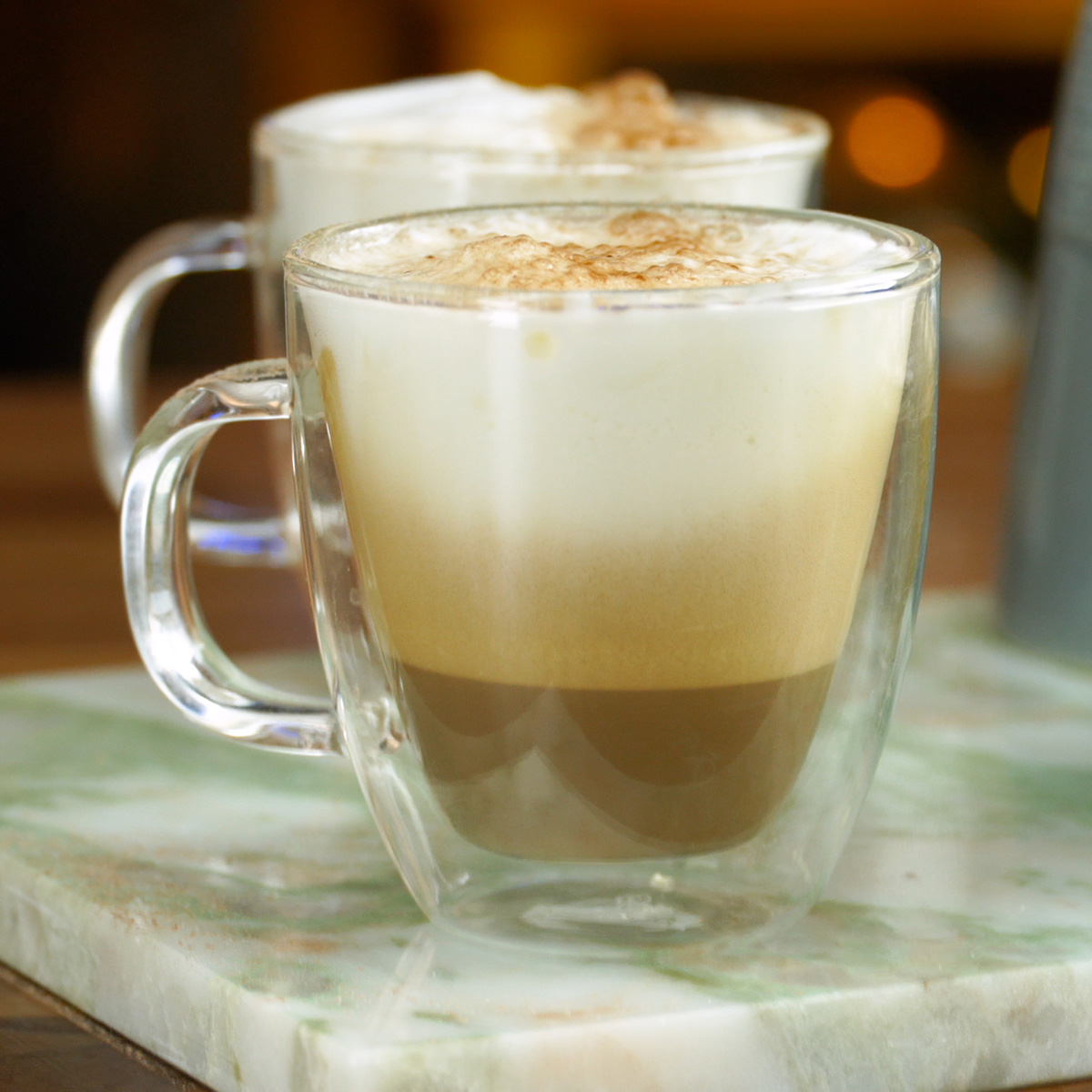 Café cremoso servido com leite e finalizado com chocolate em pó.