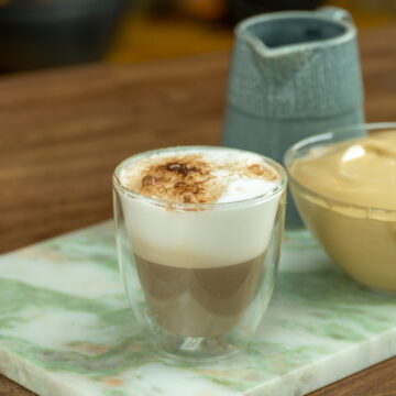 Café cremoso polvilhado com chocolate servido no copo.