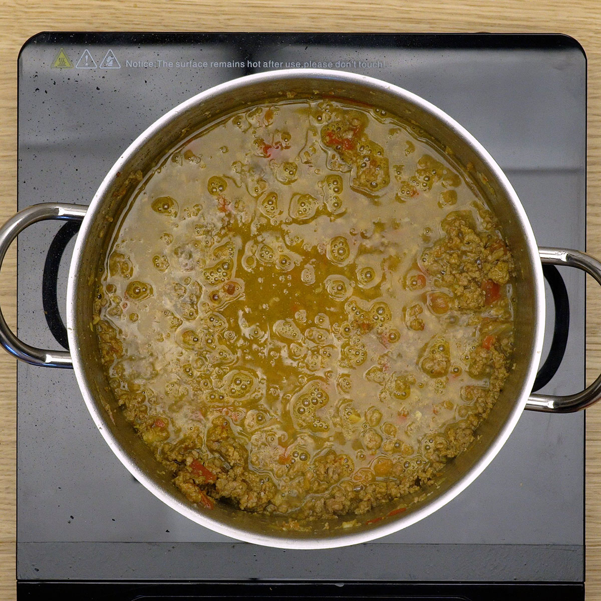 Caldo de legumes sendo incorporado à carne na panela.