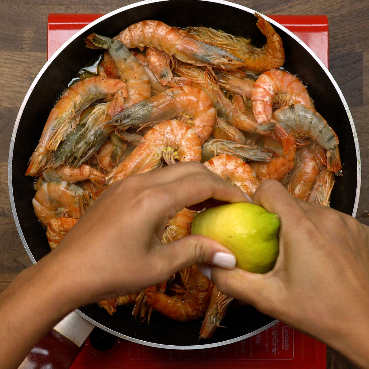 Suco de limão siciliano sendo adicionado ao camarão na frigideira.