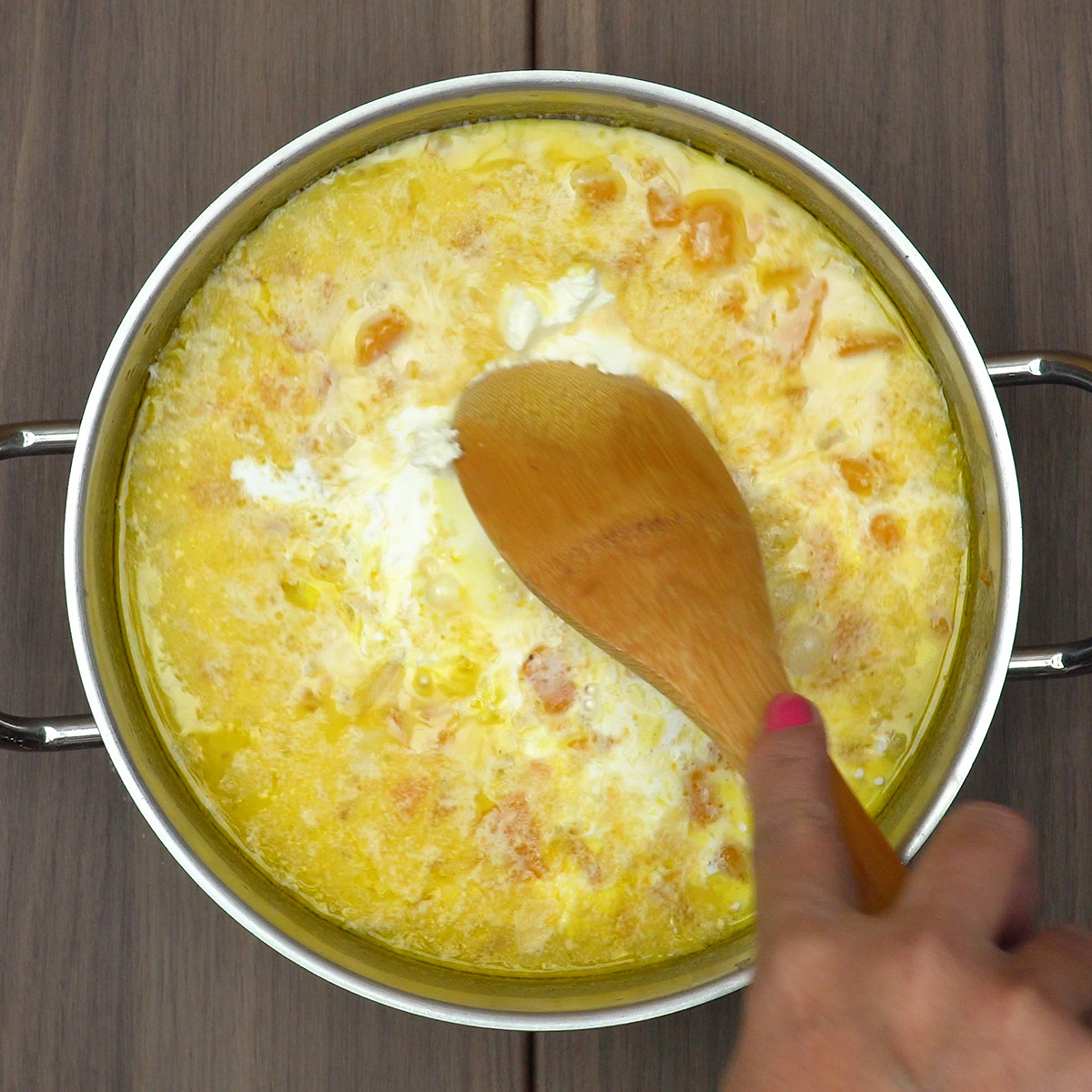 Creme de leite e requeijão sendo adicionados ao creme de abóbora.