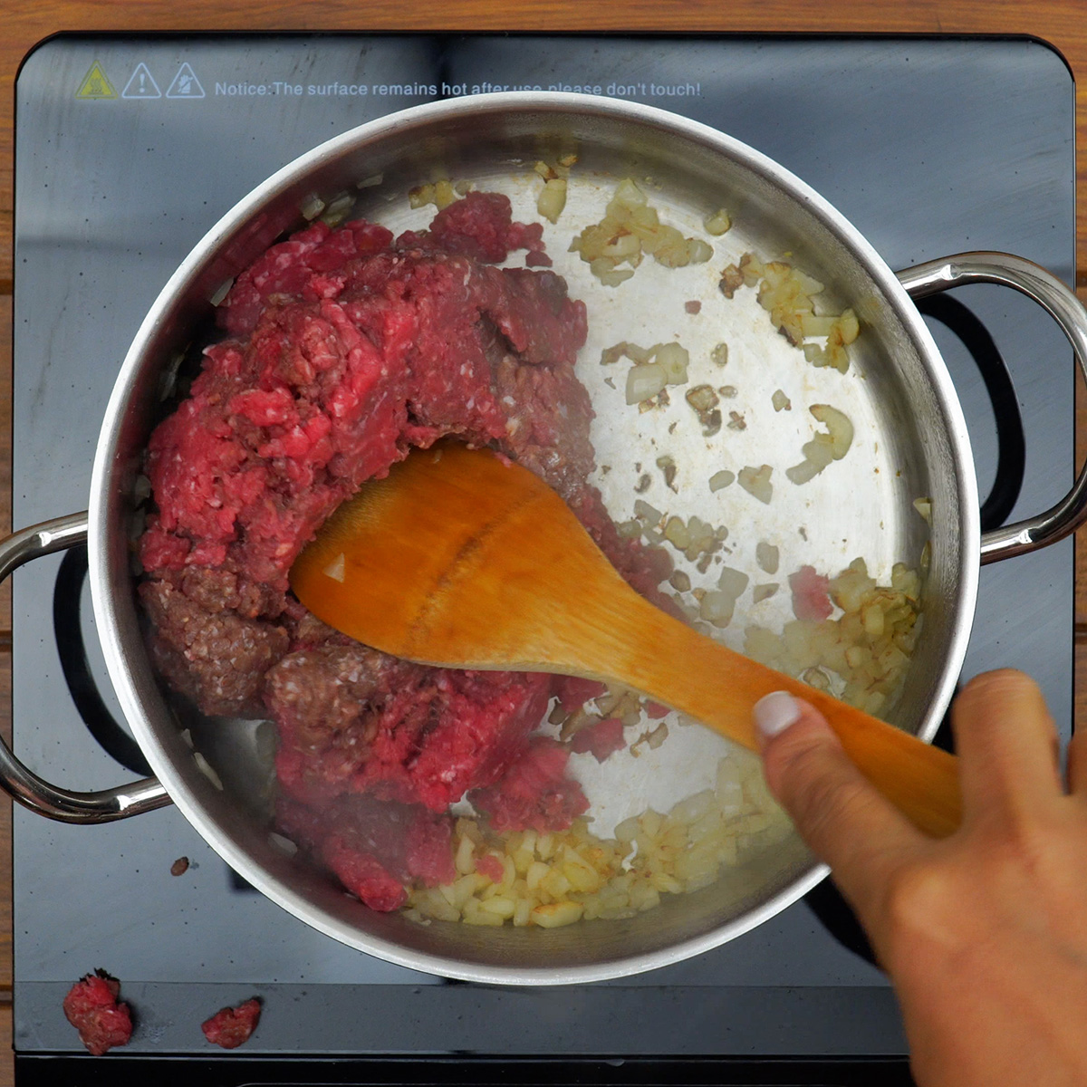 Carne moída sendo cozida com cebola e alho na panela.
