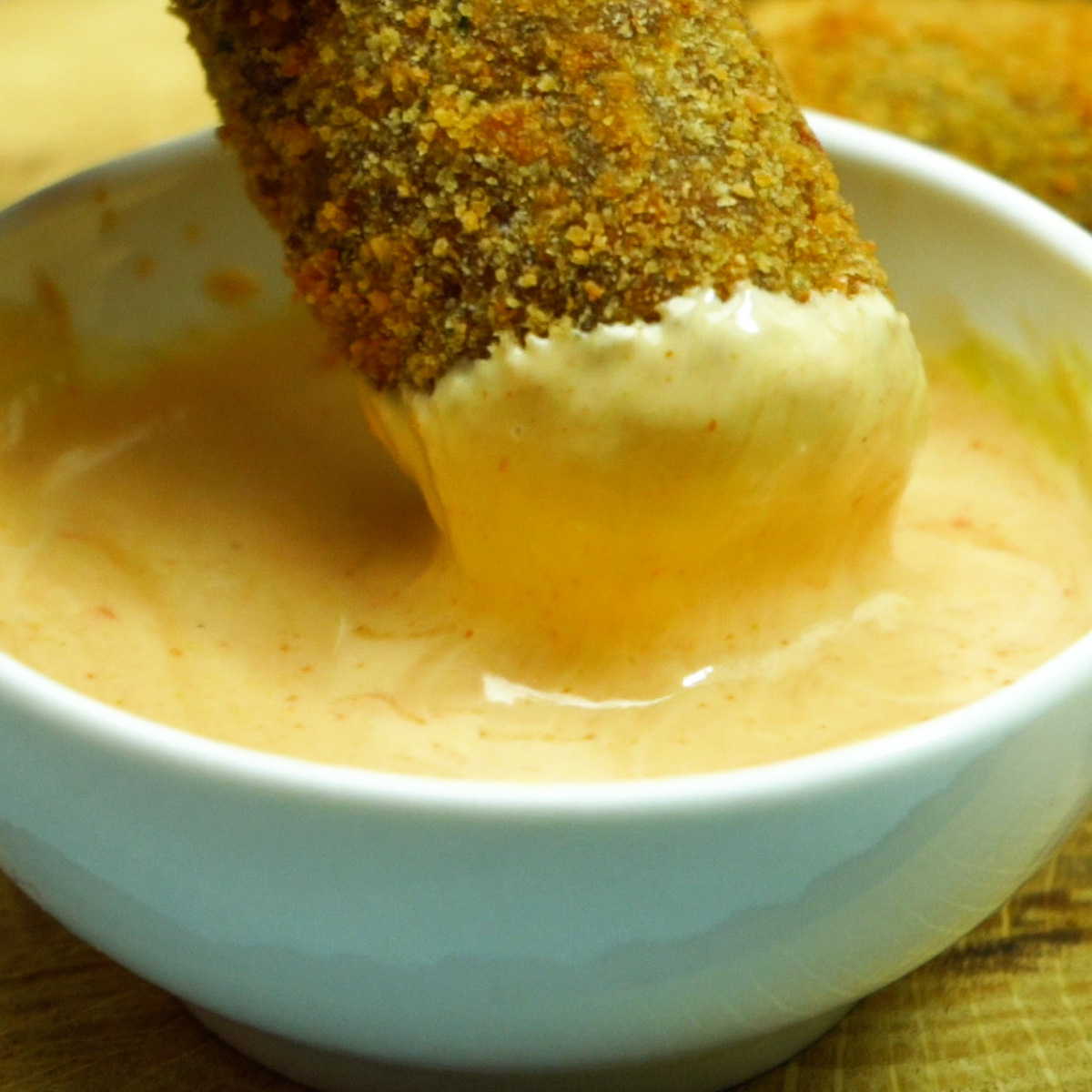 Croquete de carne sendo mergulhado no molho.