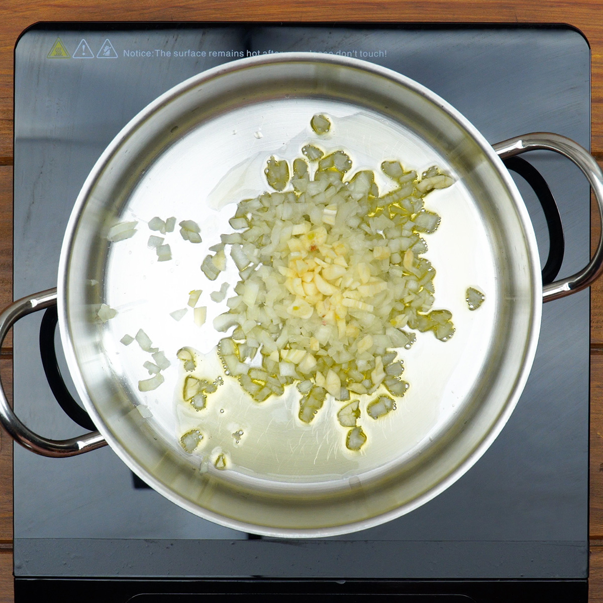 Cebola e alho sendo refogados em panela com azeite até dourarem levemente.