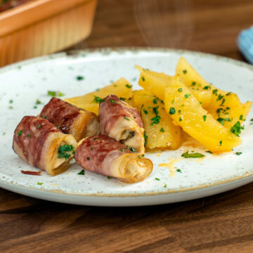 Empratamento enroladinho de peito de frango com bacon e salsa de decoração.