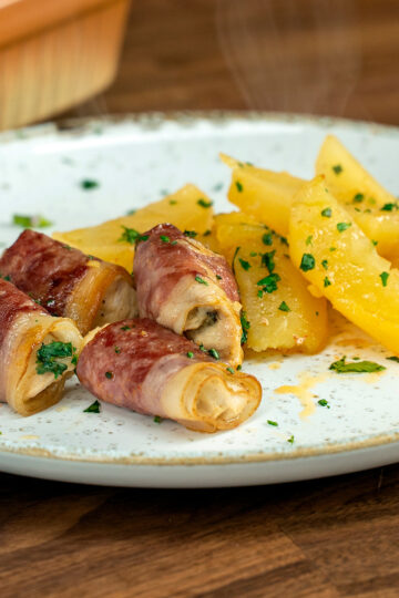 Empratamento enroladinho de peito de frango com bacon e salsa de decoração.