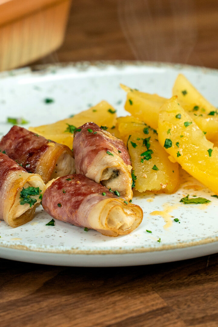 Empratamento enroladinho de peito de frango com bacon e salsa de decoração.