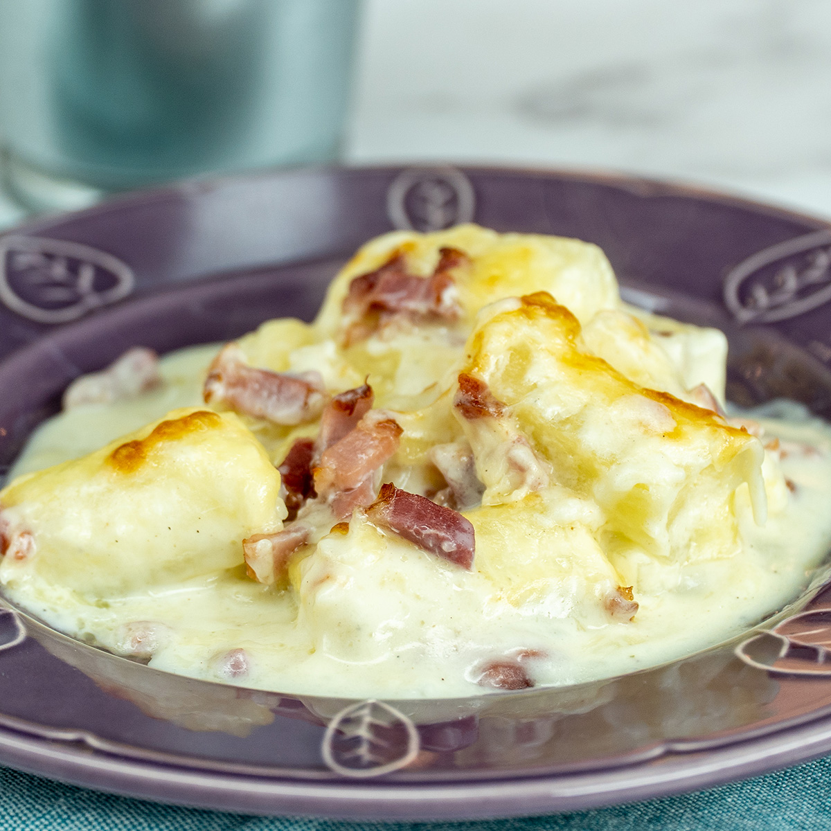 Mandioca de forno gratinada com bacon e molho branco pronta para servir.