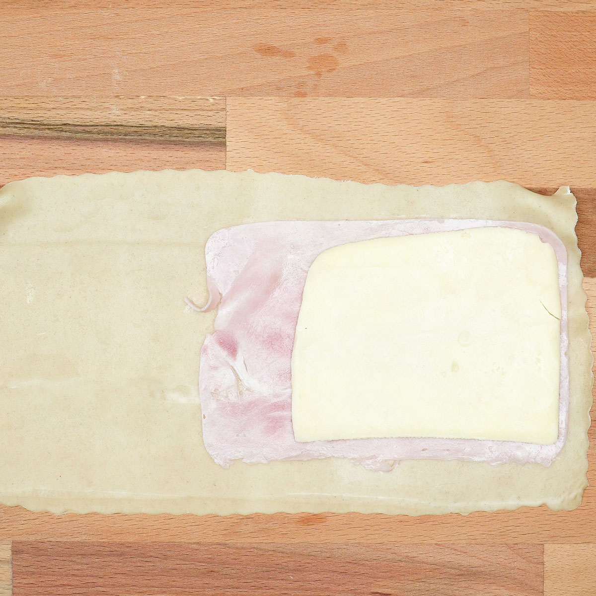 Massa de pastel com recheio de presunto e queijo posicionados.