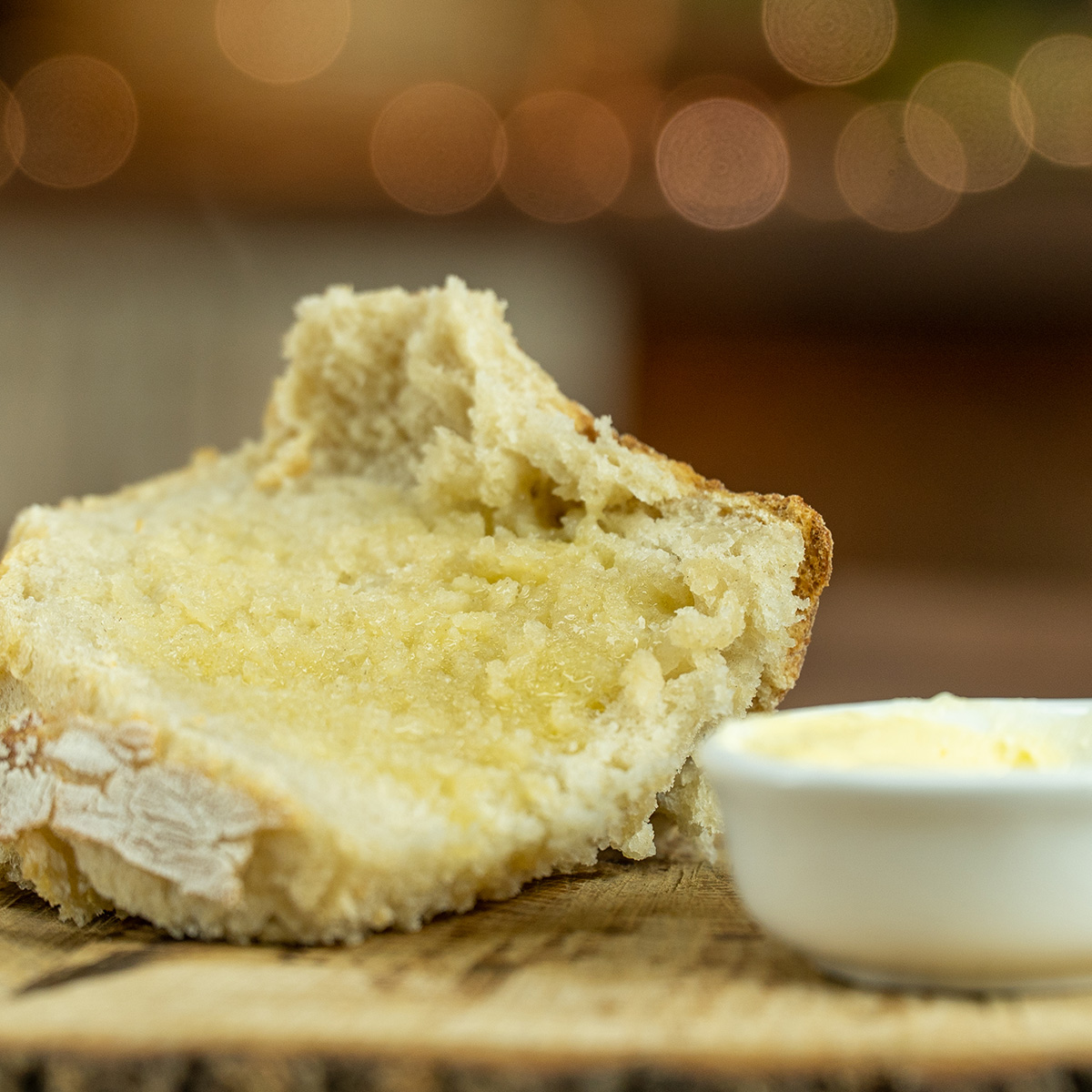 Fatia de pão de panela sendo servida com manteiga.