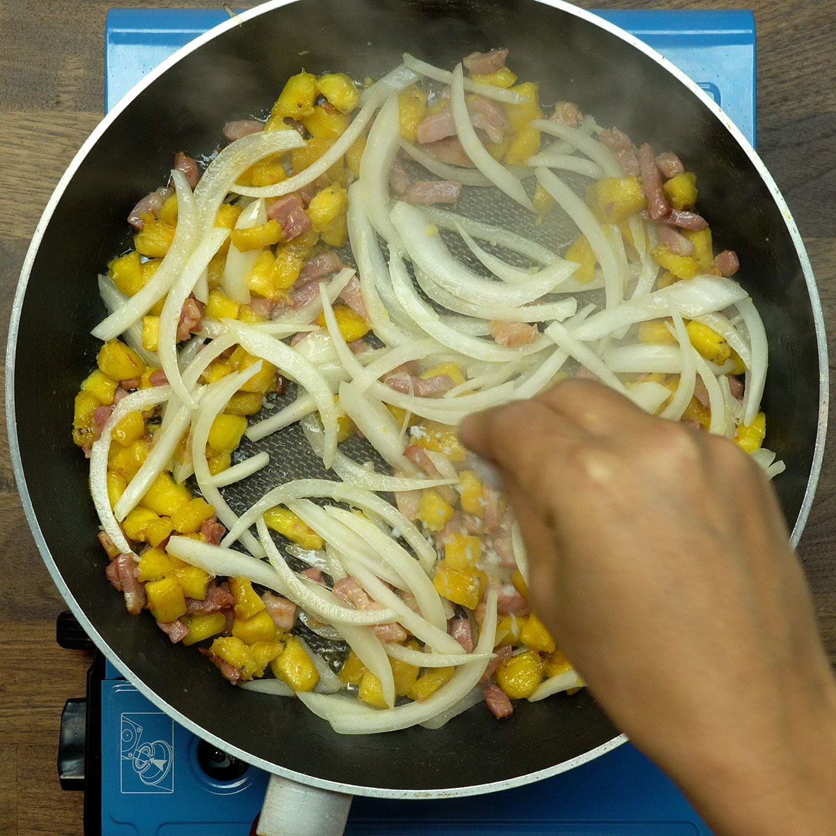 Farofa sendo temperada com sal durante o preparo na frigideira.