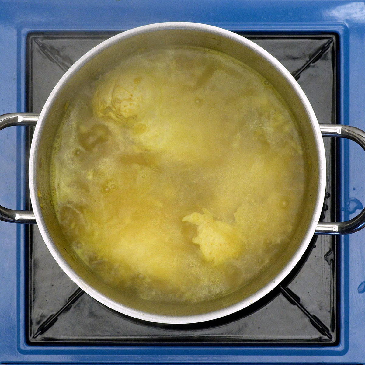 Peito de frango cozinhando em panela com temperos.