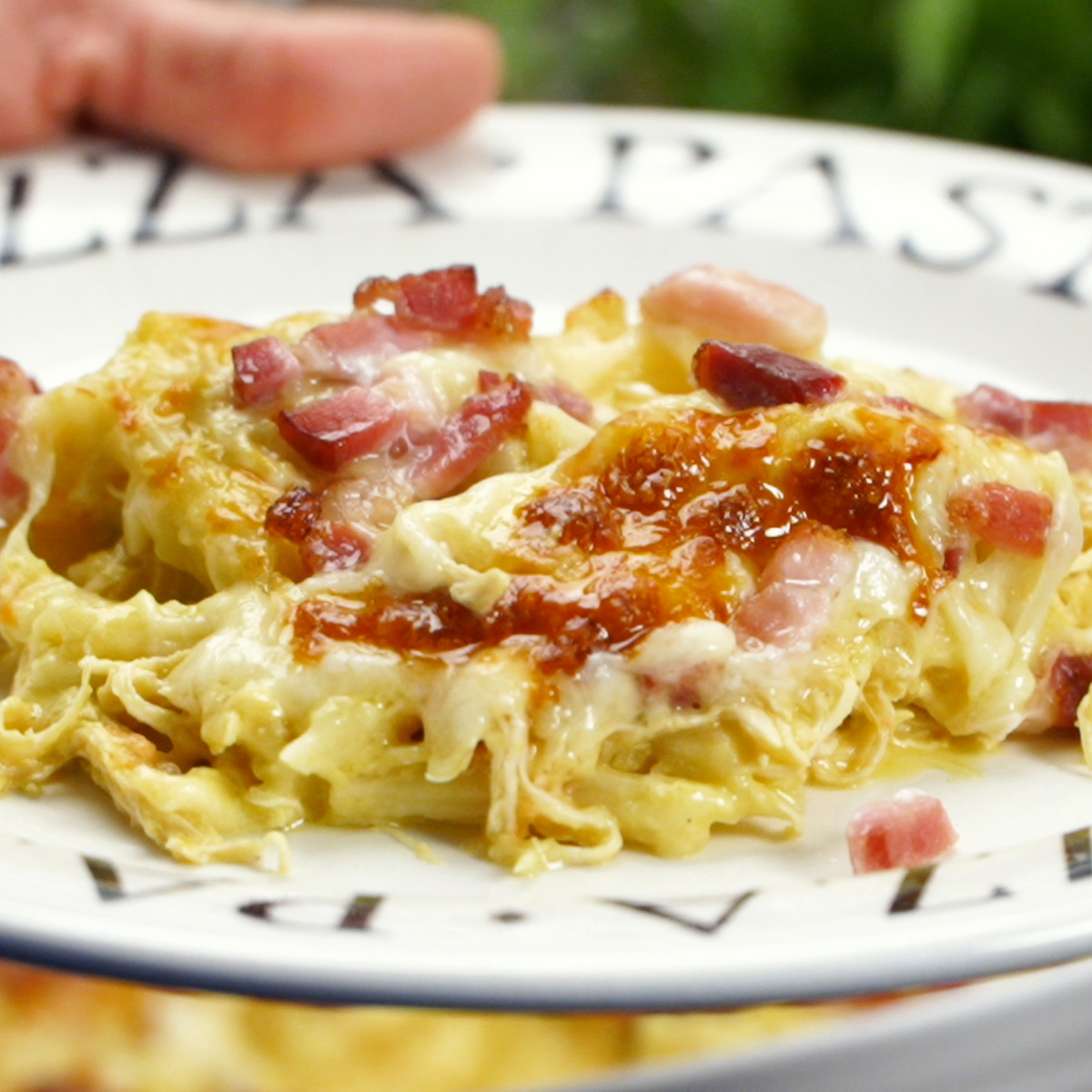 Macarrão penne cremoso com frango e bacon servido quente com queijo gratinado.