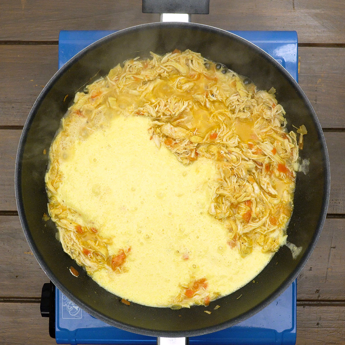 Molho cremoso de milho com frango sendo misturado na panela.