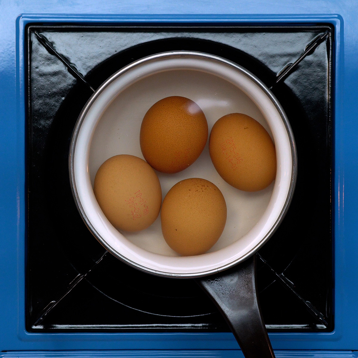 Ovos cozinhando em panela com água para preparar maionese de ovos cozidos.