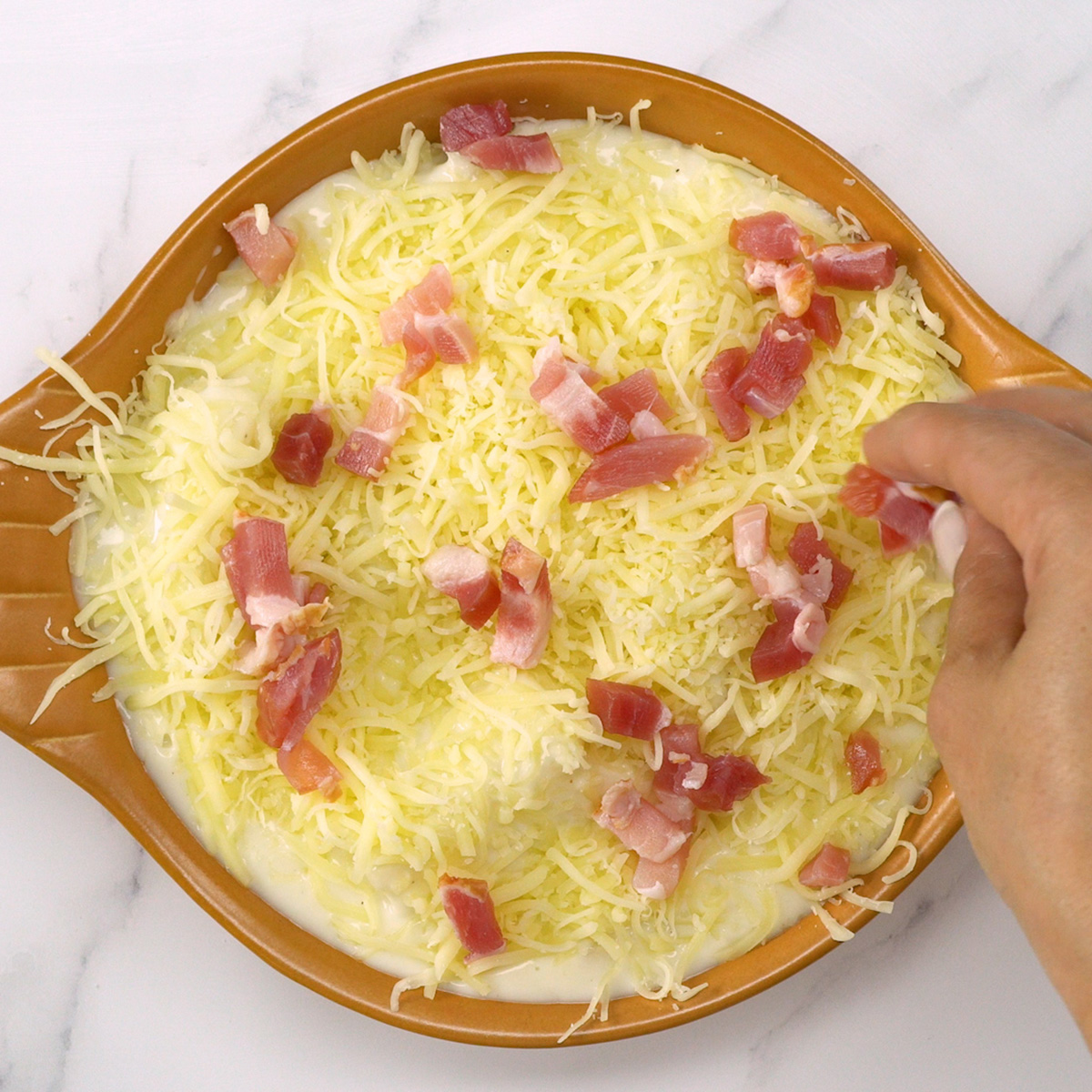 Refratário com mandioca, queijo e bacon pronto para ir ao forno.