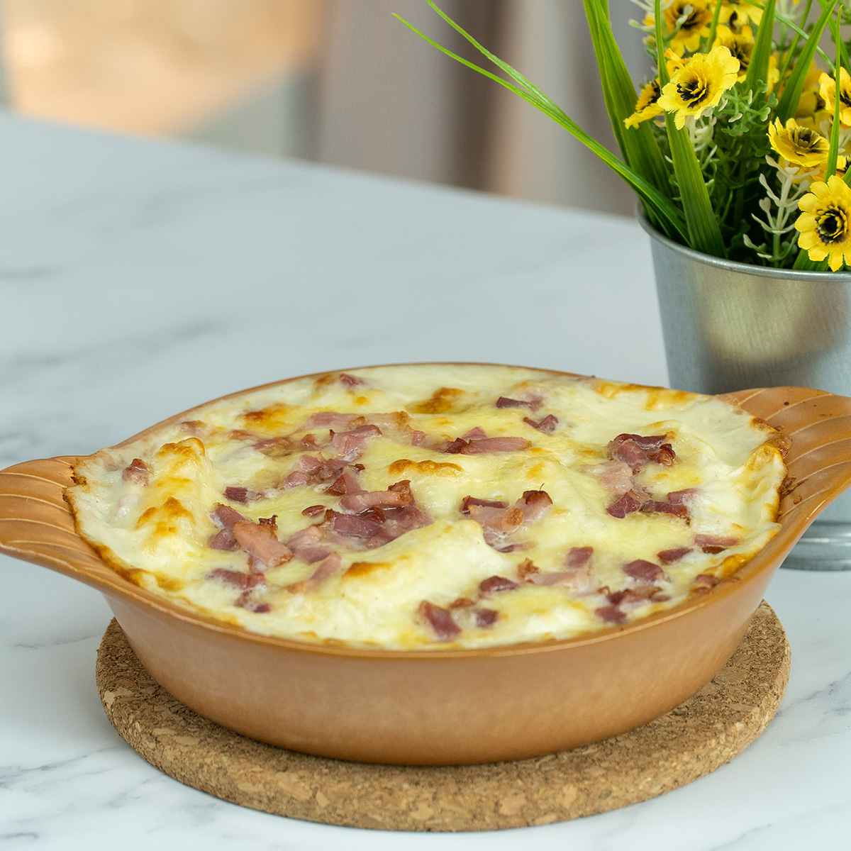 Mandioca de forno gratinada com bacon saindo do forno pronto para ser servido.