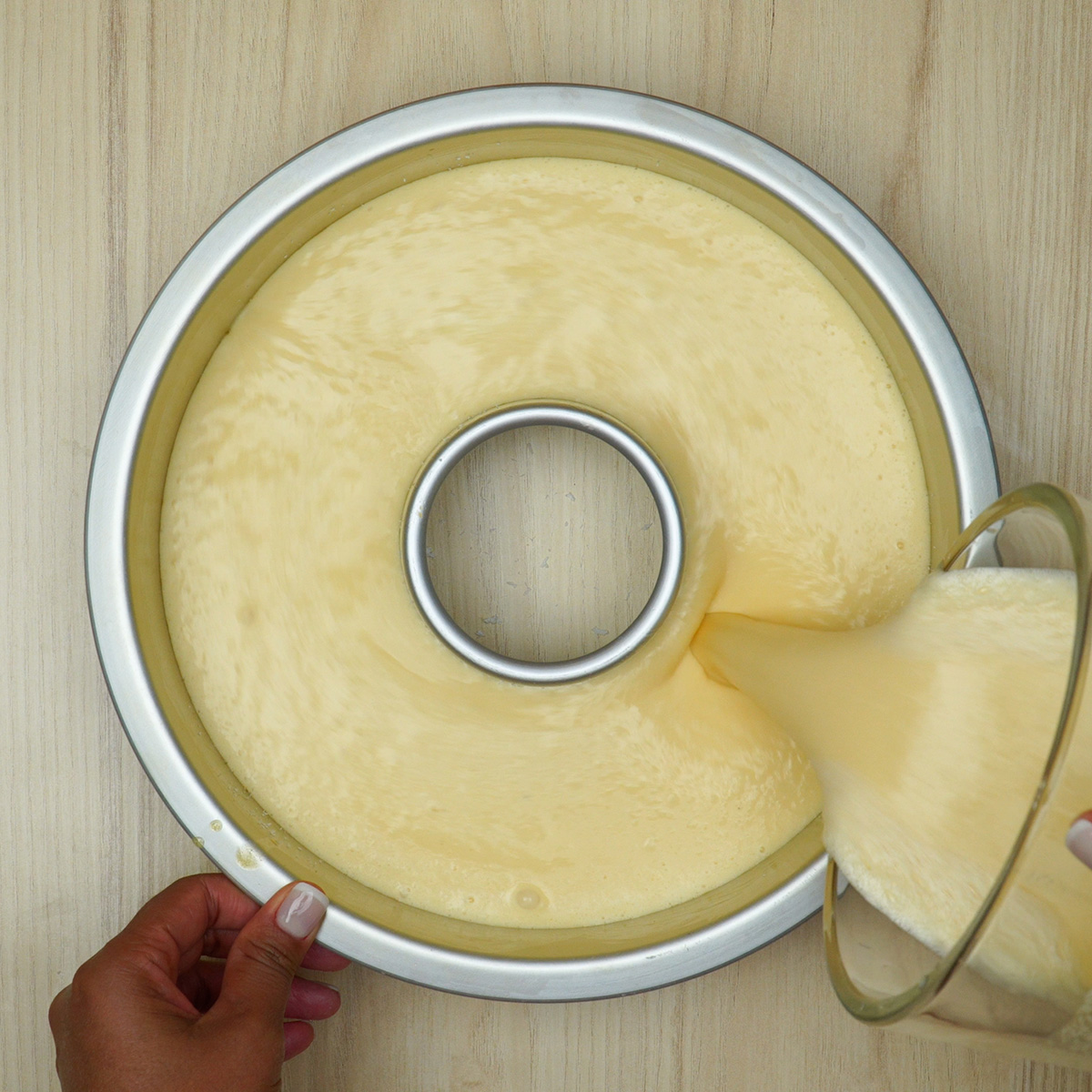 Massa do bolo de coco cremoso no liquidificador sendo despejada na forma.