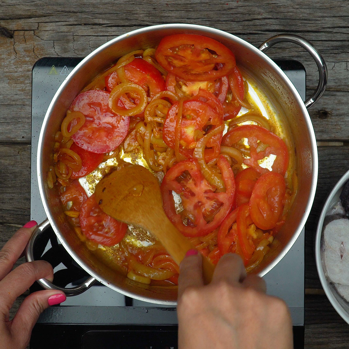 Tomates em rodelas sobre a base temperada com colorau na panela.