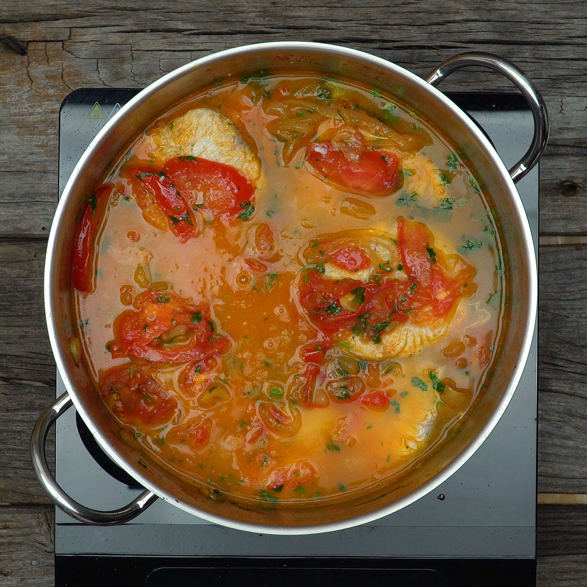 Postas de pescada cozinhando no caldo da moqueca capixaba tradicional.