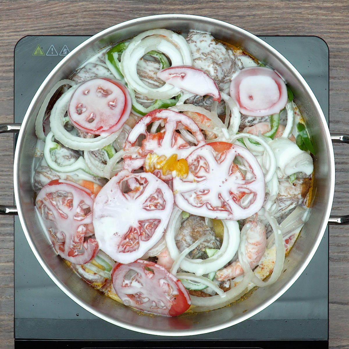 Moqueca de peixe cozinhando com leite de coco até o molho apurar.