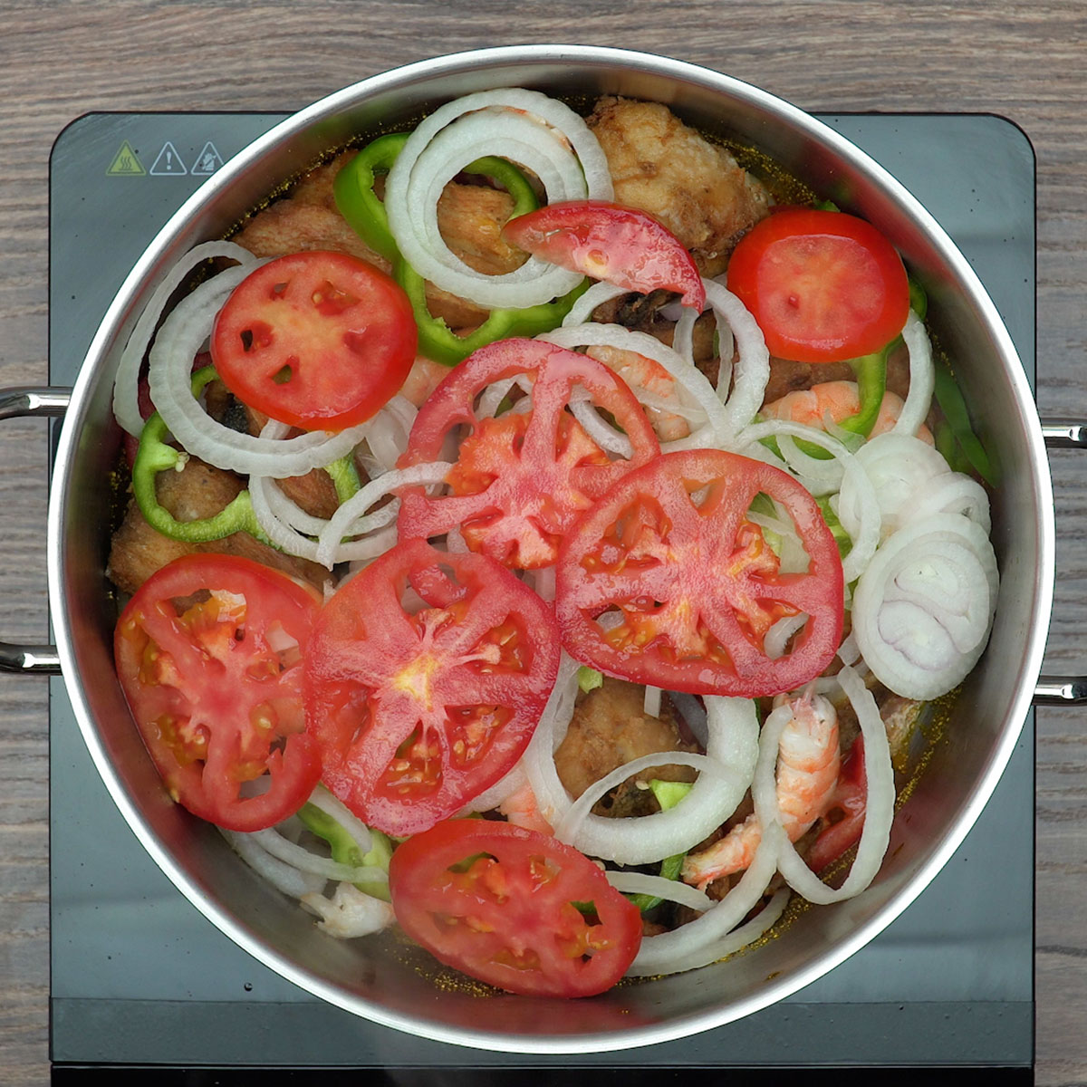 Montagem da moqueca com peixe, camarão, tomate e pimentão.