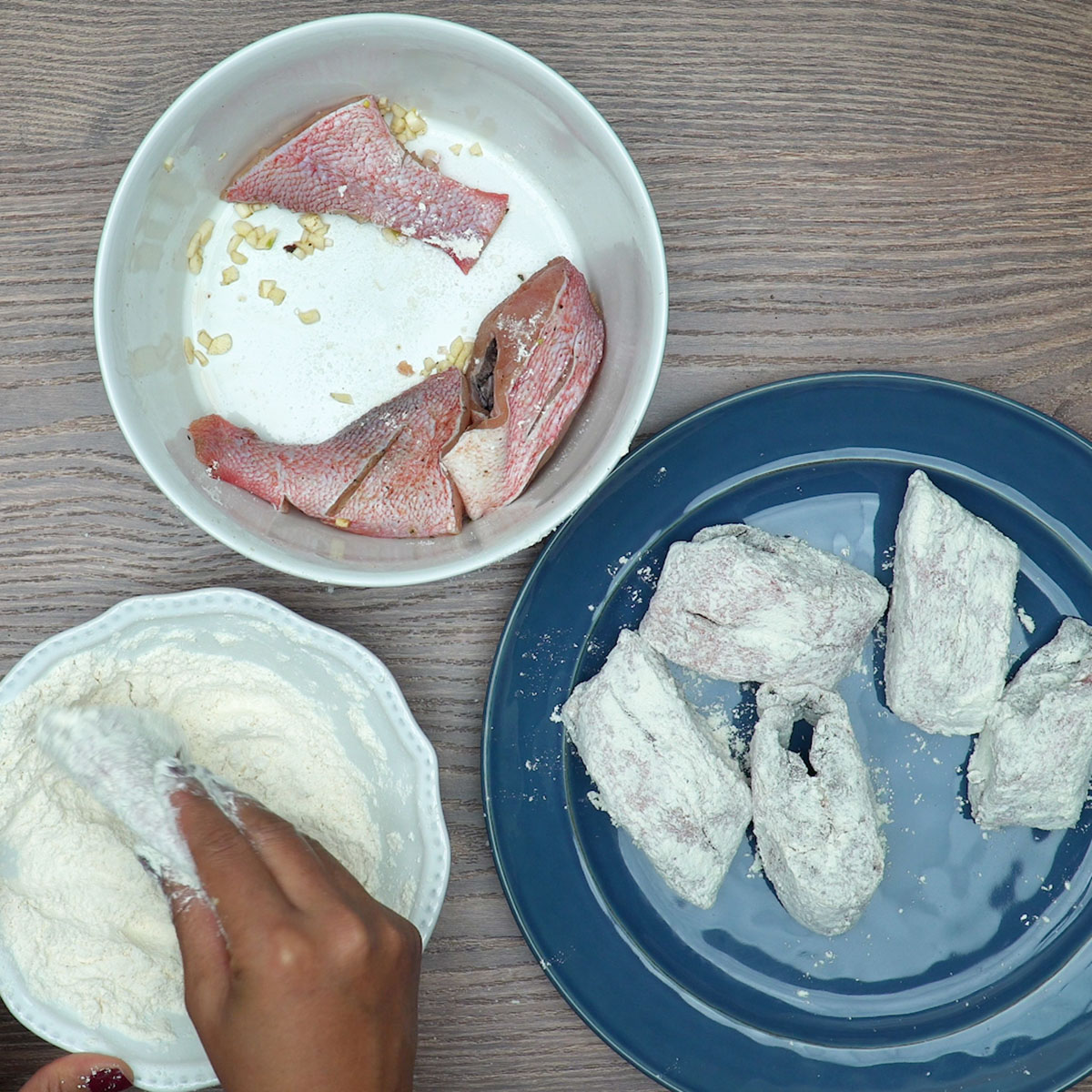 Pedaços de peixe sendo passados na farinha antes de fritar.