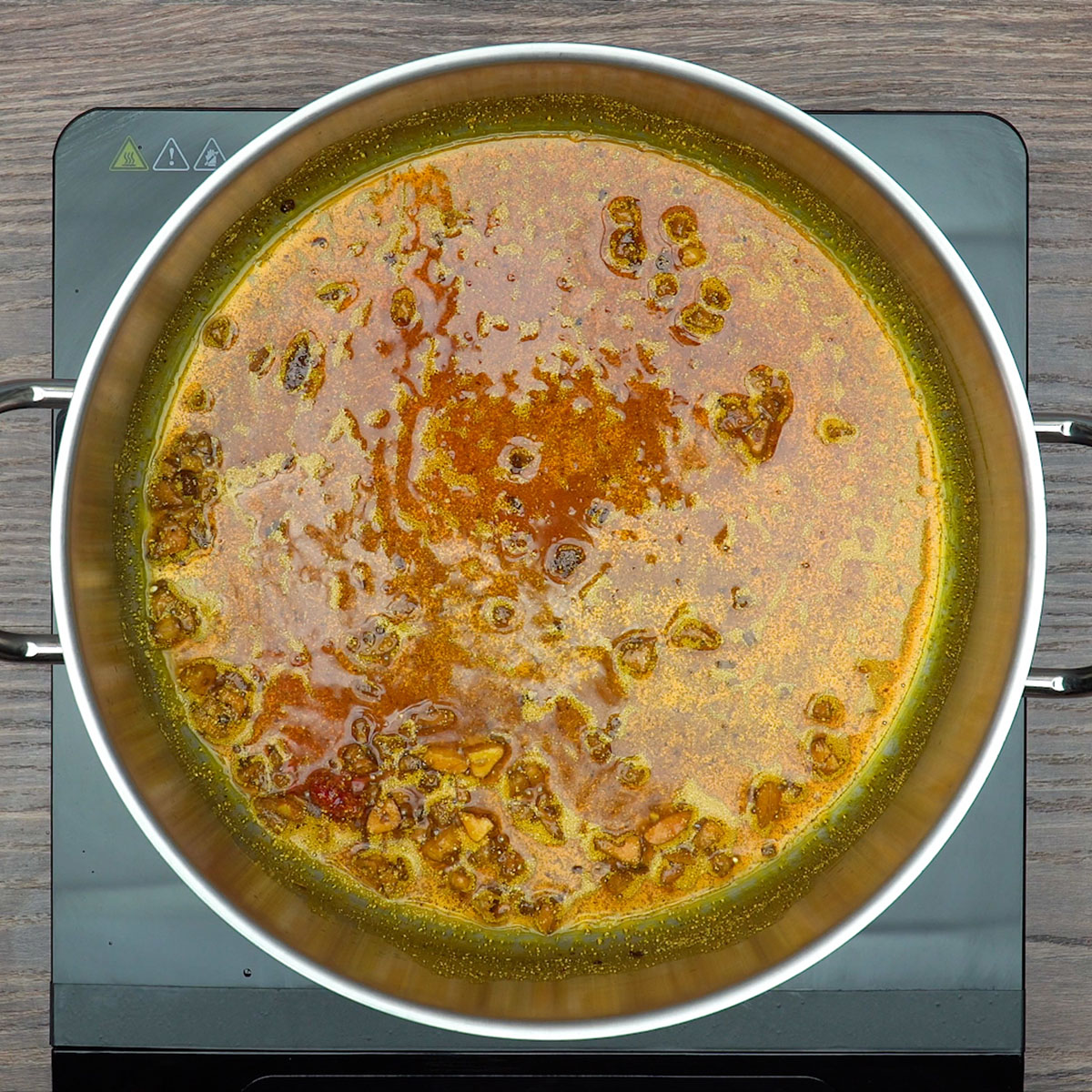 Alho e colorau refogando no azeite para formar a base da moqueca de peixe.