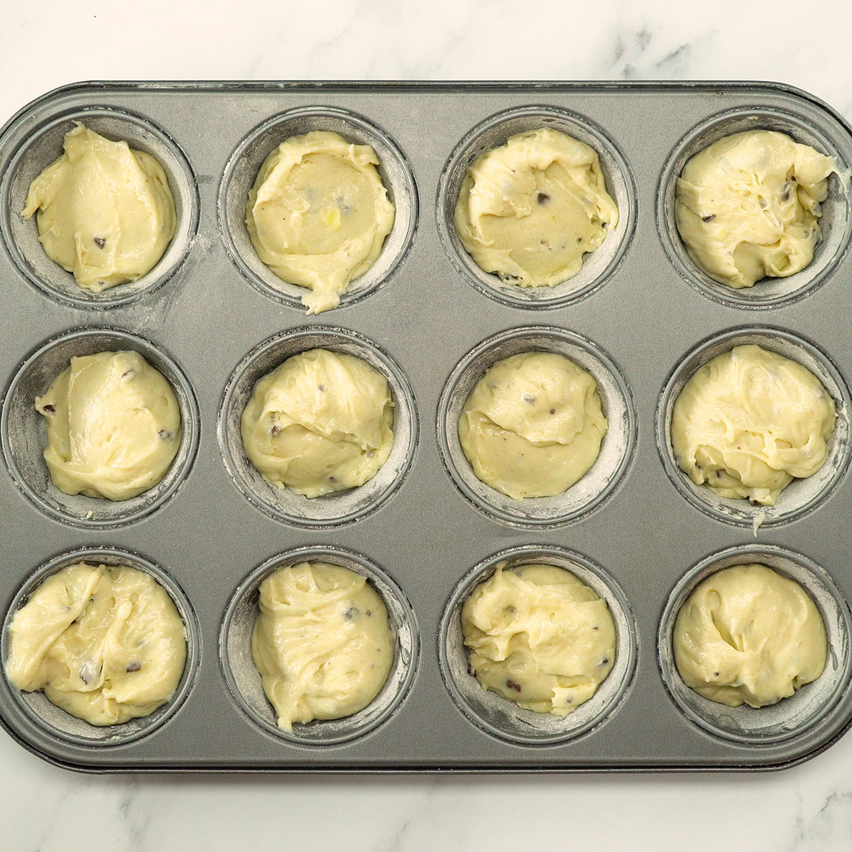 Massa de muffins distribuída nas formas antes de assar.