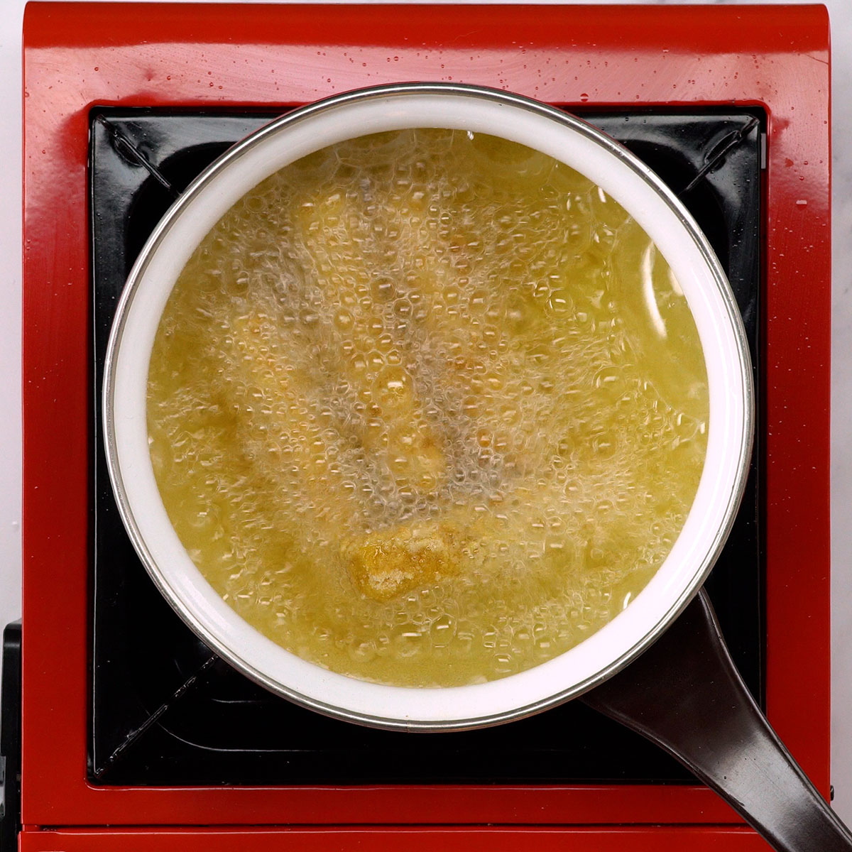 Palitos de muçarela fritando em óleo quente.