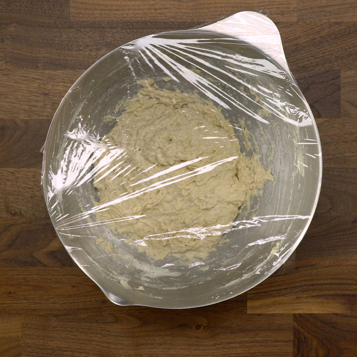 Massa de pão coberta descansando em uma tigela após a mistura inicial.